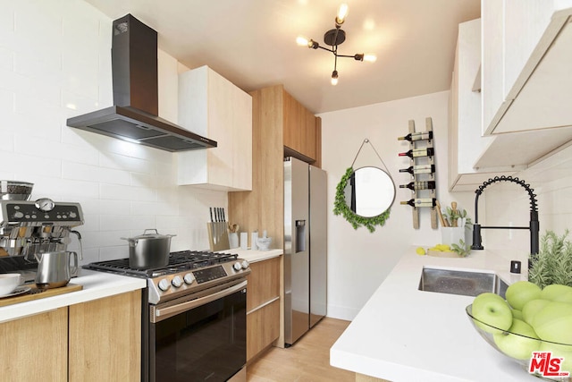 kitchen with wall chimney range hood, sink, decorative backsplash, light wood-type flooring, and appliances with stainless steel finishes