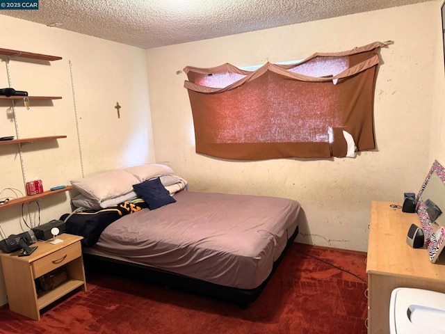 bedroom featuring a textured ceiling and dark colored carpet