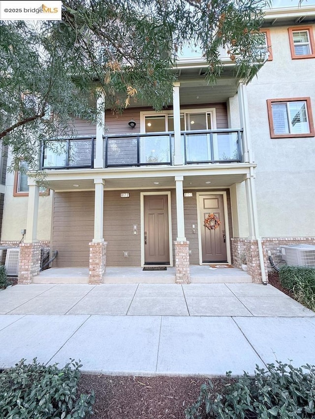 view of front of property featuring a balcony and central AC