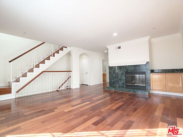 unfurnished living room featuring crown molding, dark wood-type flooring, and a high end fireplace