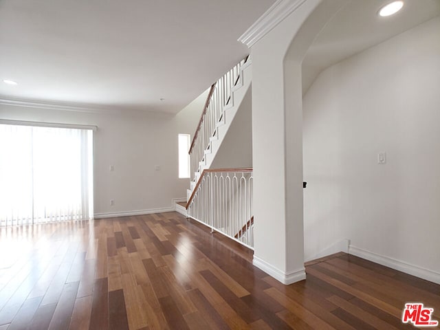 spare room featuring ornamental molding and dark wood-type flooring