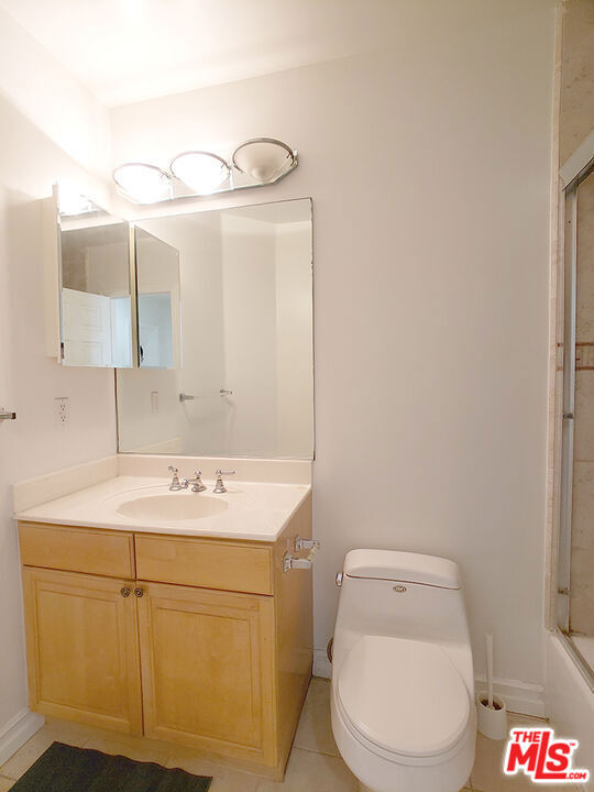 full bathroom featuring tile patterned flooring, vanity, toilet, and bath / shower combo with glass door