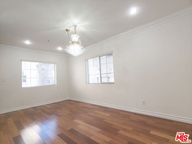 unfurnished room with dark hardwood / wood-style flooring, crown molding, a wealth of natural light, and a chandelier