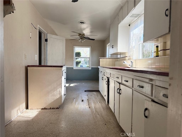 kitchen with decorative backsplash, sink, white cabinetry, and ceiling fan