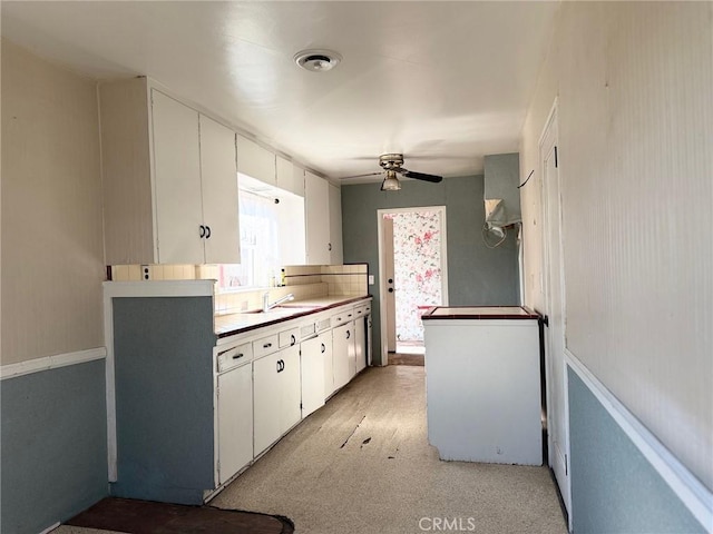 kitchen with ceiling fan, white cabinetry, and sink