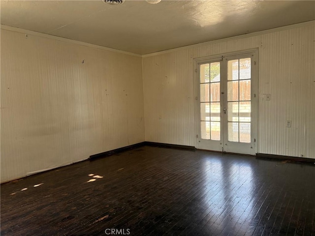 spare room featuring dark wood-type flooring, ornamental molding, and french doors