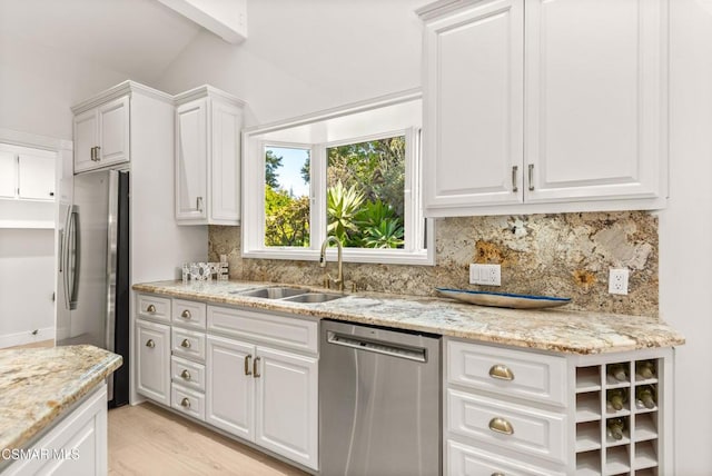 kitchen featuring sink, stainless steel appliances, light stone countertops, decorative backsplash, and white cabinets