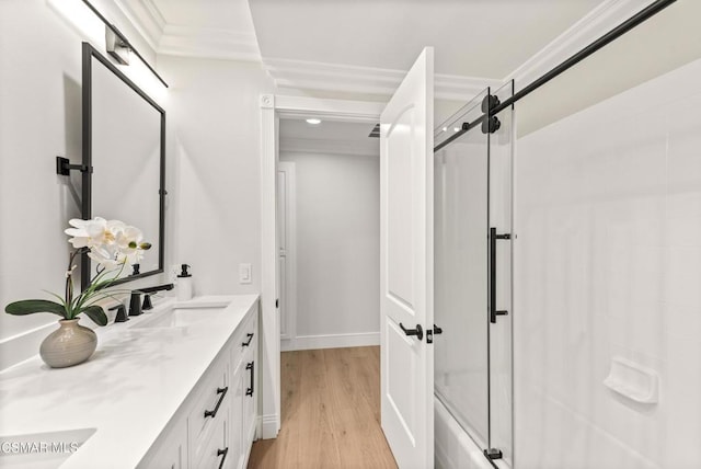 bathroom with vanity, hardwood / wood-style floors, crown molding, and enclosed tub / shower combo