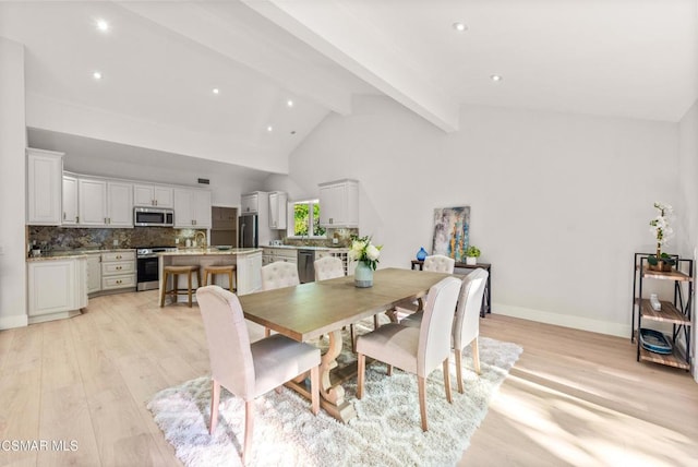 dining room with lofted ceiling with beams and light wood-type flooring