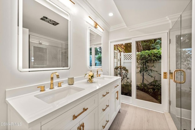 bathroom with an enclosed shower, vanity, wood-type flooring, and ornamental molding