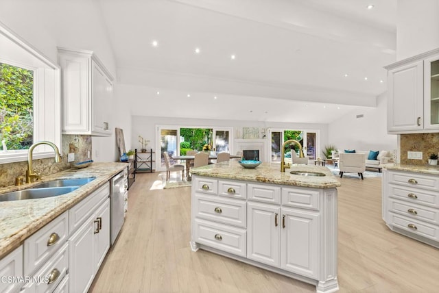 kitchen with sink, stainless steel dishwasher, white cabinets, and light stone counters