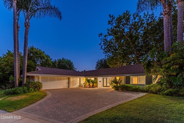 ranch-style home featuring a garage and a front lawn