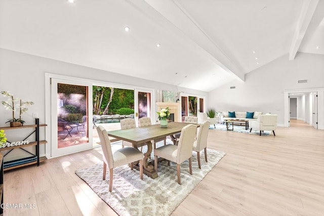 dining area featuring light hardwood / wood-style flooring, high vaulted ceiling, and beamed ceiling