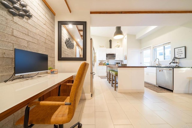 kitchen with sink, a breakfast bar area, stainless steel appliances, white cabinets, and kitchen peninsula