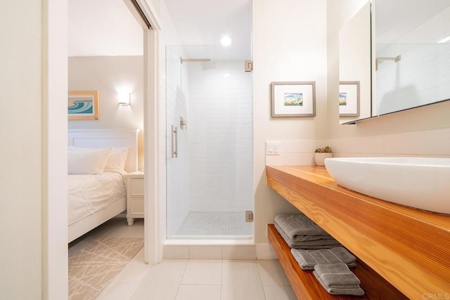 bathroom with tile patterned floors, a shower with shower door, and sink