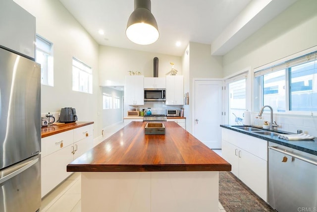 kitchen featuring a kitchen island, appliances with stainless steel finishes, butcher block counters, sink, and white cabinets