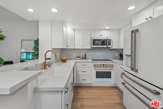 kitchen with oven, high end fridge, white cabinetry, and sink