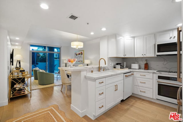 kitchen featuring pendant lighting, white appliances, white cabinets, a kitchen bar, and kitchen peninsula