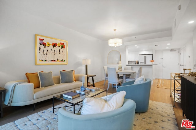 living room with light hardwood / wood-style floors and an inviting chandelier