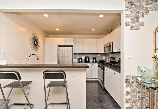 kitchen featuring white cabinets, appliances with stainless steel finishes, kitchen peninsula, and a breakfast bar area