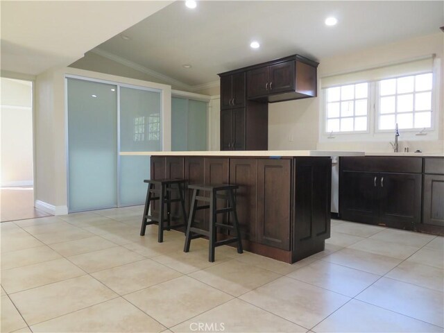 kitchen featuring a kitchen island, a kitchen bar, lofted ceiling, and crown molding