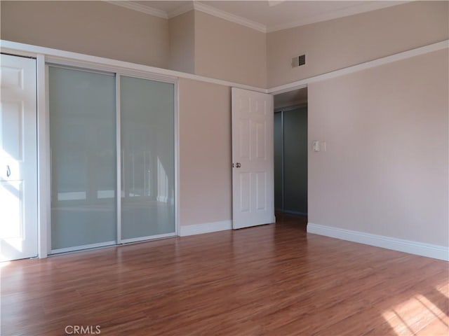 empty room with hardwood / wood-style flooring, crown molding, and elevator