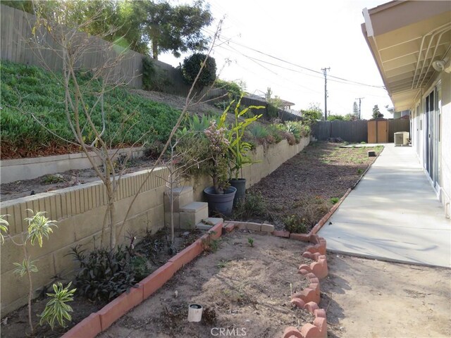 view of yard with central AC unit and a storage shed