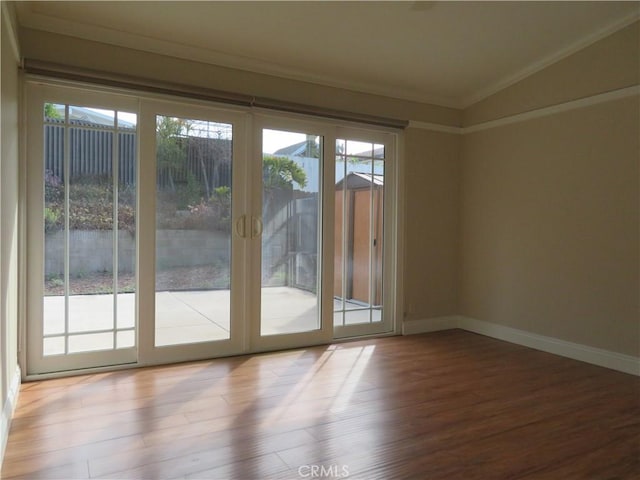 doorway with crown molding, wood-type flooring, and vaulted ceiling