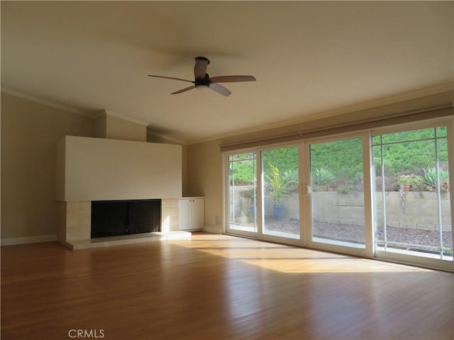 unfurnished living room featuring a tile fireplace, ceiling fan, light hardwood / wood-style flooring, and ornamental molding