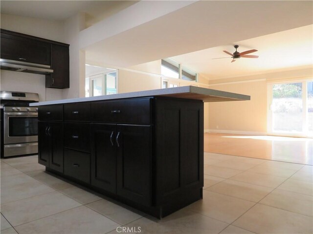 kitchen with ceiling fan, light tile patterned flooring, stainless steel range oven, and extractor fan