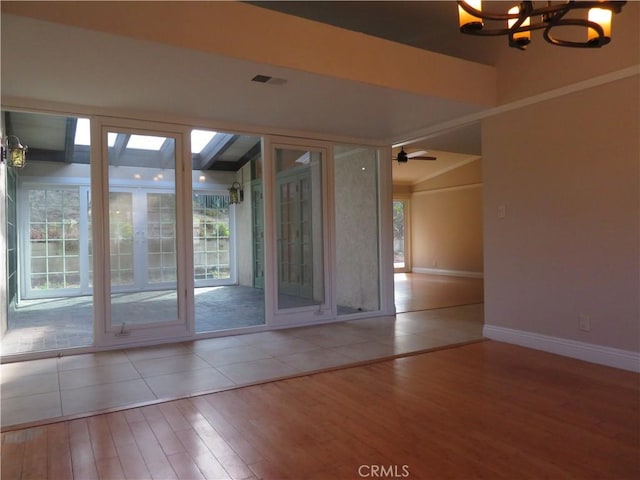 empty room with hardwood / wood-style floors and ceiling fan with notable chandelier