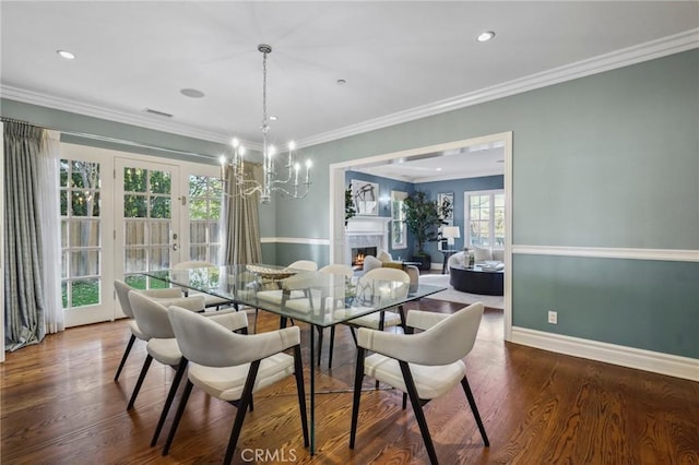 dining area featuring a warm lit fireplace, baseboards, ornamental molding, wood finished floors, and a notable chandelier