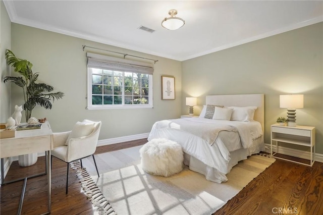 bedroom with ornamental molding, visible vents, baseboards, and wood finished floors