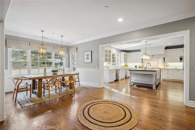 dining area featuring dark wood-style flooring, crown molding, recessed lighting, wainscoting, and baseboards