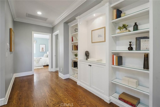 hallway featuring attic access, baseboards, visible vents, dark wood-style flooring, and crown molding