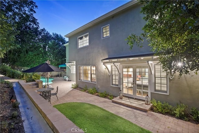 rear view of house featuring stucco siding, a patio, and french doors