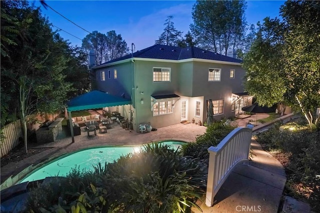 back of property with a fenced in pool, a patio, stucco siding, outdoor lounge area, and fence