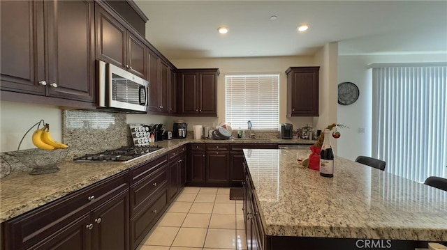 kitchen featuring light stone counters, a kitchen island, a sink, and stainless steel appliances