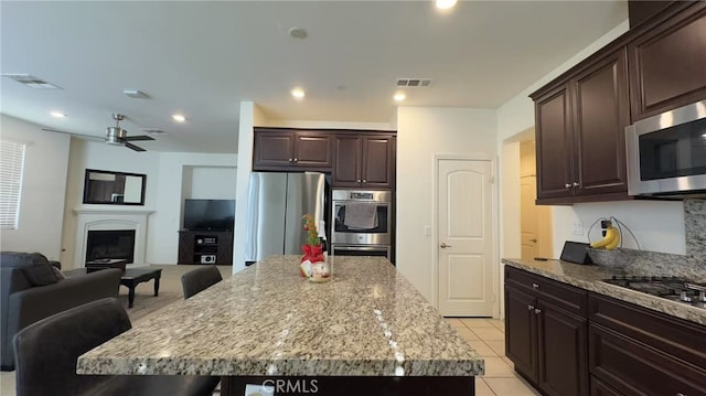 kitchen featuring a kitchen breakfast bar, ceiling fan, light tile patterned floors, a kitchen island, and stainless steel appliances