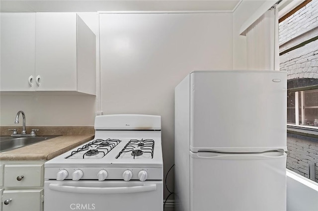 kitchen with sink, white cabinets, and white appliances