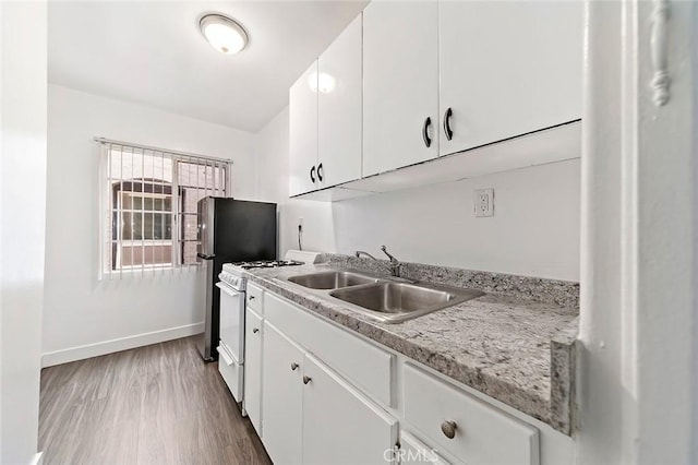 kitchen with light stone countertops, white gas range oven, sink, light hardwood / wood-style flooring, and white cabinets