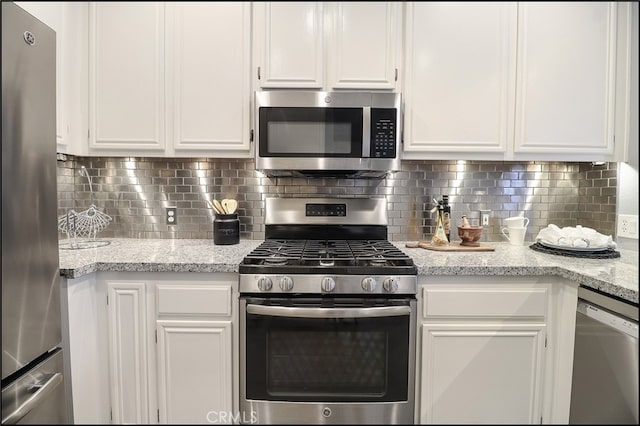 kitchen featuring white cabinets, backsplash, light stone counters, and stainless steel appliances