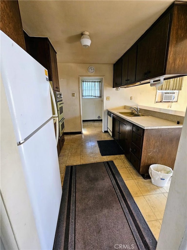 kitchen with dark brown cabinetry, dishwasher, sink, and white fridge