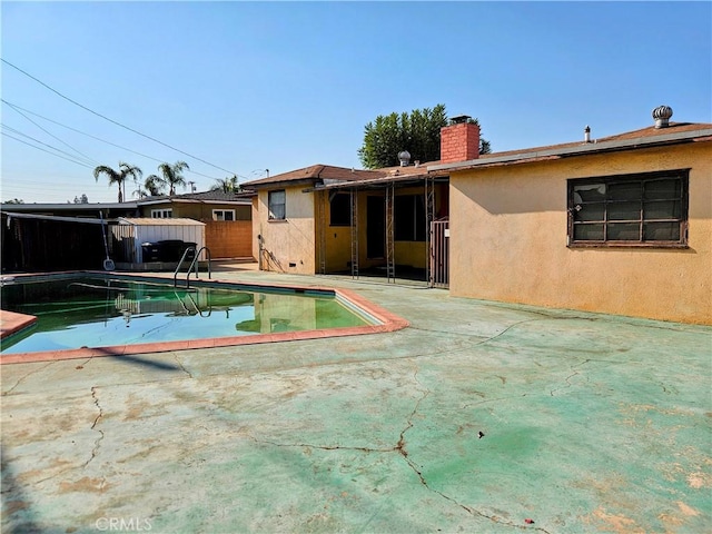 rear view of property featuring a fenced in pool and a patio area