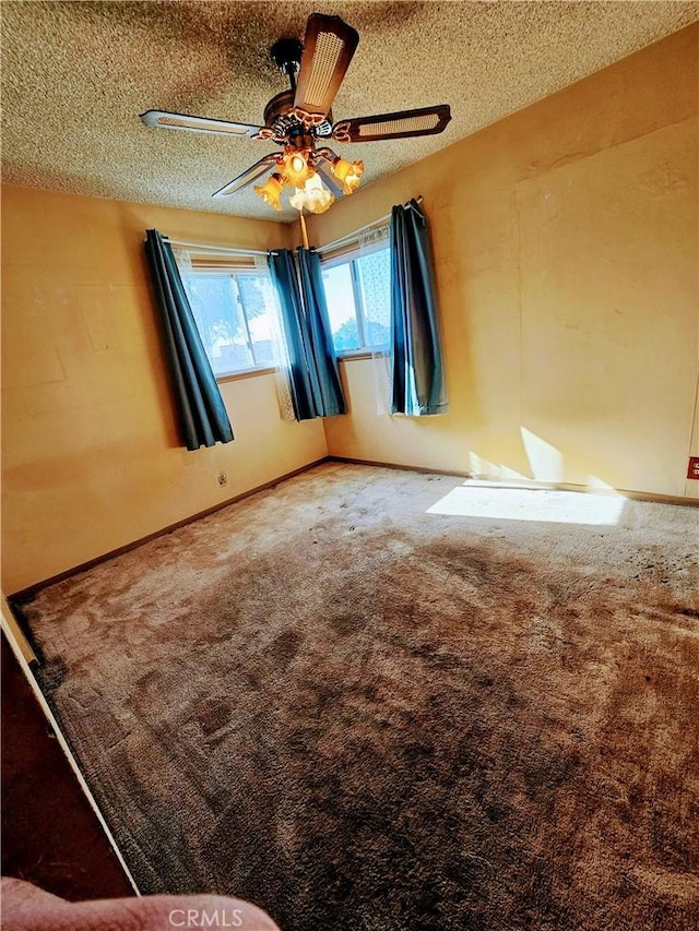 carpeted spare room featuring ceiling fan and a textured ceiling