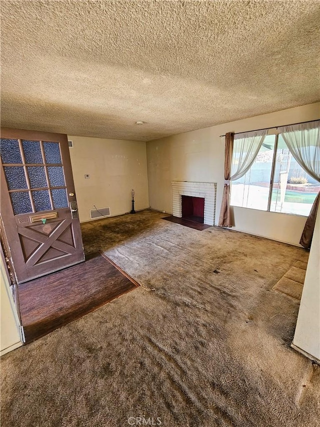 unfurnished living room with carpet flooring, a fireplace, and a textured ceiling