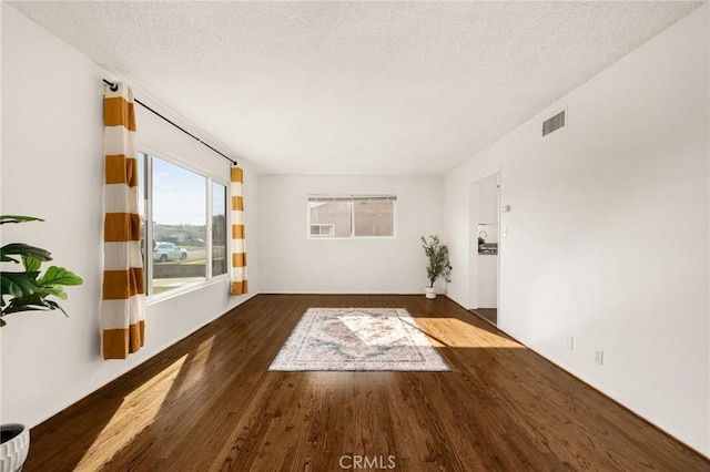 unfurnished living room with dark hardwood / wood-style flooring and a textured ceiling