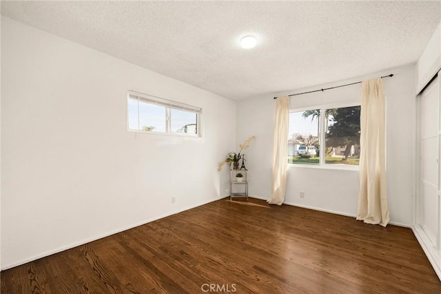 empty room featuring a textured ceiling and dark wood-type flooring