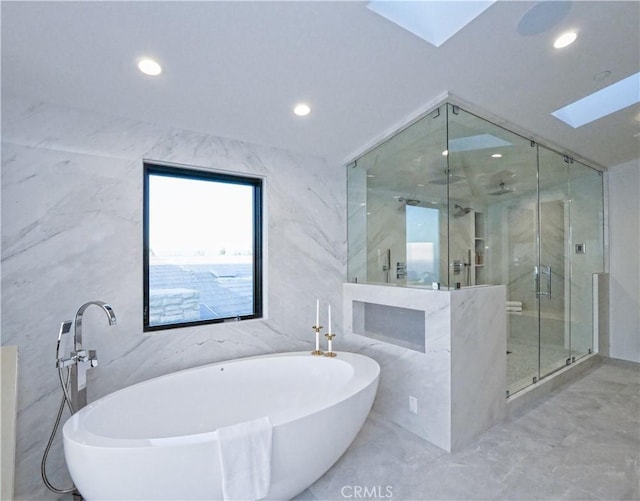 bathroom featuring shower with separate bathtub, a skylight, and tile walls