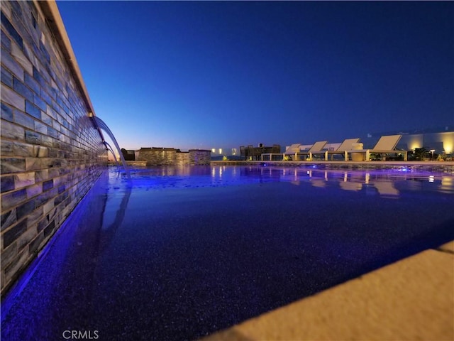 pool at dusk featuring a water view